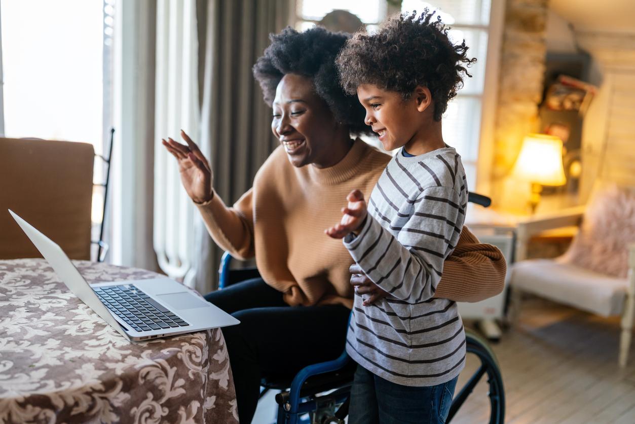 Mother in wheelchair expresses excitement with her son over good news on the computer on receiving disability benefits