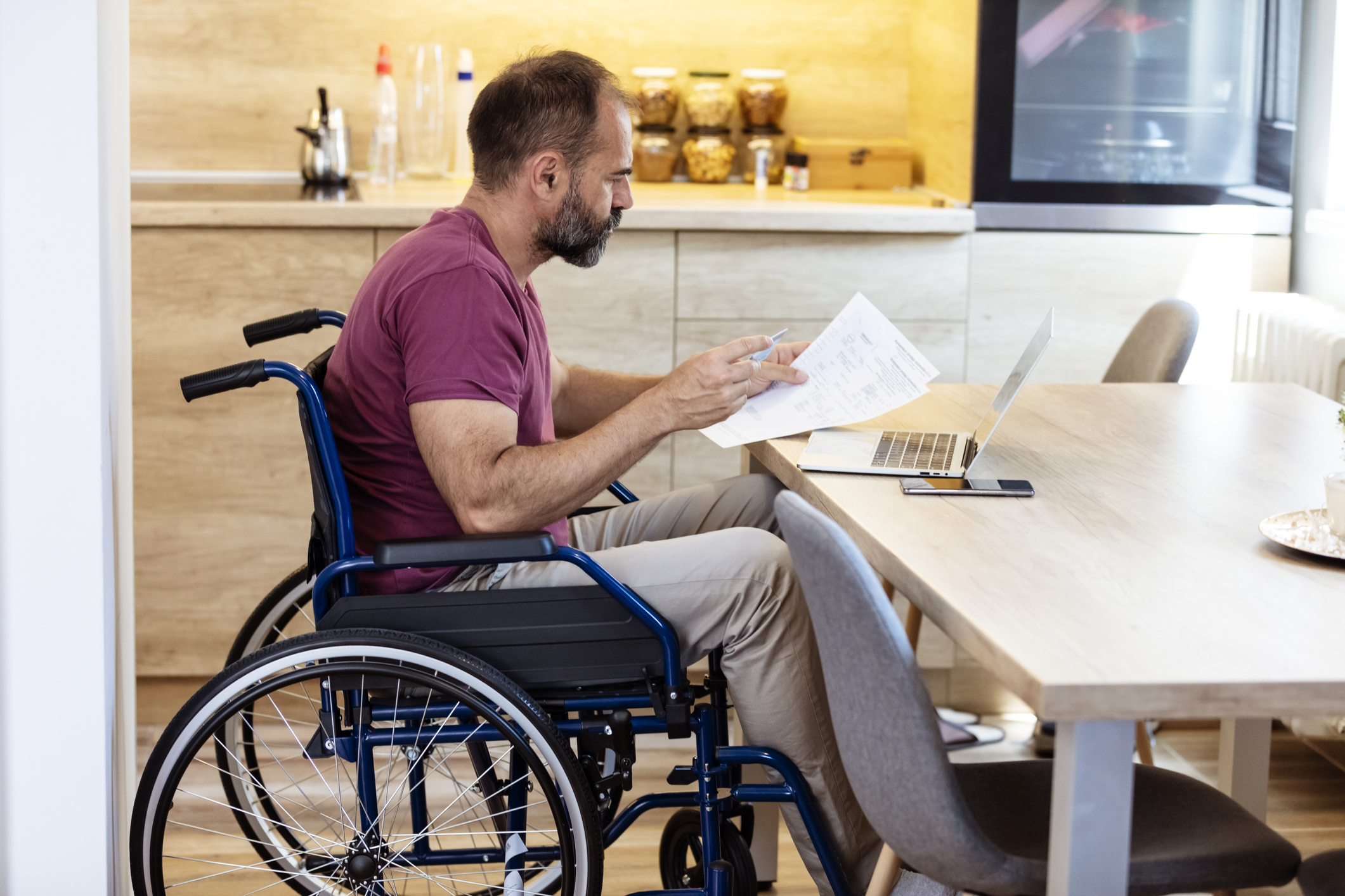 Man in wheelchair working on laptop at home. 
