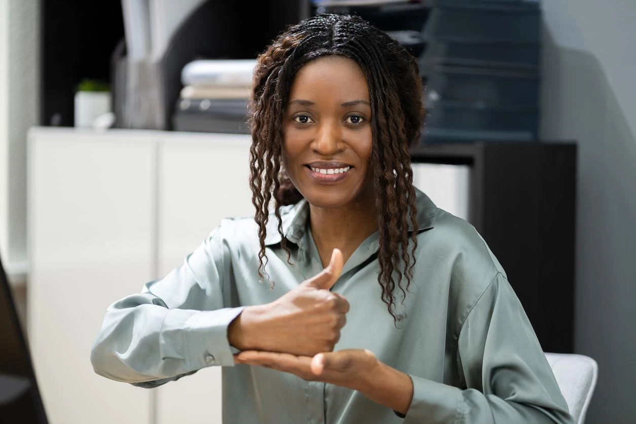 Professional black woman uses American Sign Language (ASL) to communicate at work