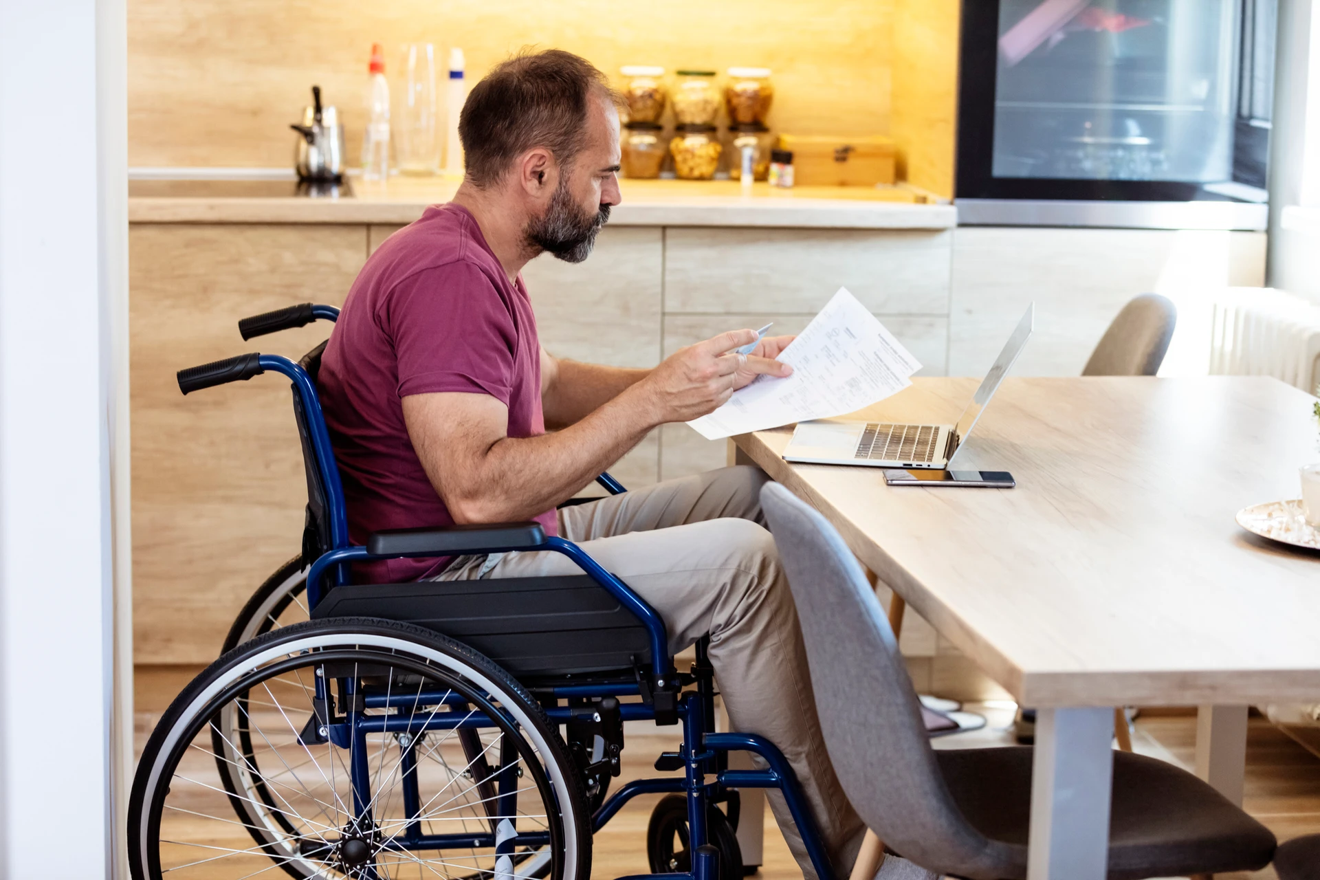 Man in wheelchair working on laptop at home. 